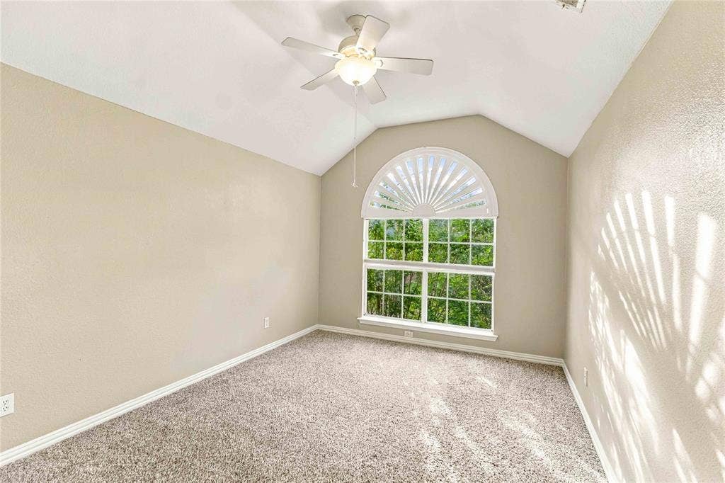 Vaulted ceiling, arched window with decorative fanlight, and ceiling fan with integrated lighting