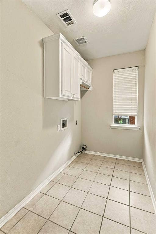 Utility room featuring neutral ceramic tile flooring, white shaker-style wall-mounted cabinetry, and a window with horizontal blinds