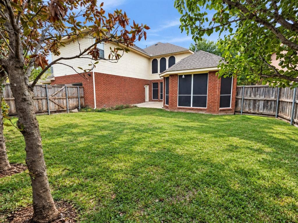 Backyard featuring a grass lawn, perimeter wood fencing, masonry and siding exterior, multi-pane windows with screens, and a concrete patio