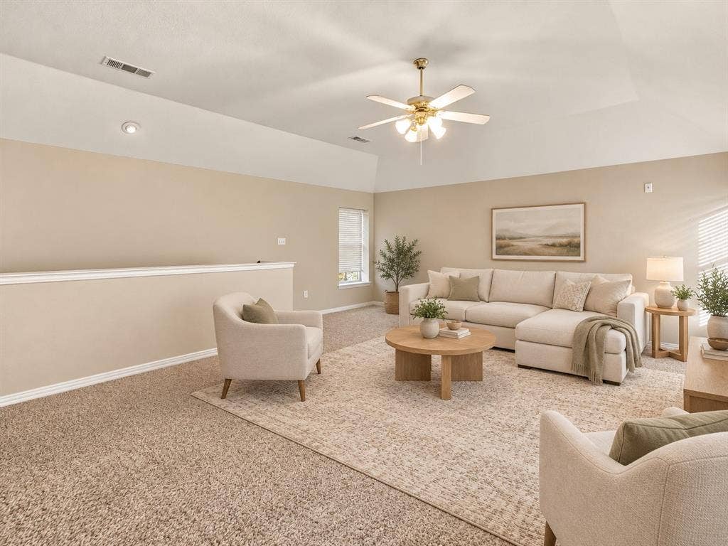 Vaulted ceiling featuring a central multi-blade ceiling fan with integrated light fixture and neutral wall-to-wall carpeting