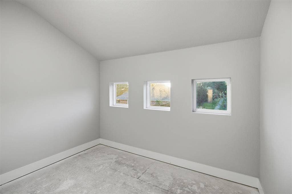 1408 Rockcliff Street, Plano, TX 75093 Vaulted ceiling room featuring three inset square windows and concrete flooring