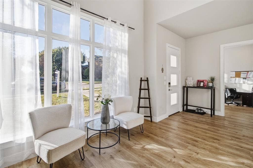 1408 Rockcliff Street, Plano, TX 75093 Vaulted ceiling, expansive floor-to-ceiling windows, white entry door with frosted glass panels, and wood-finish flooring