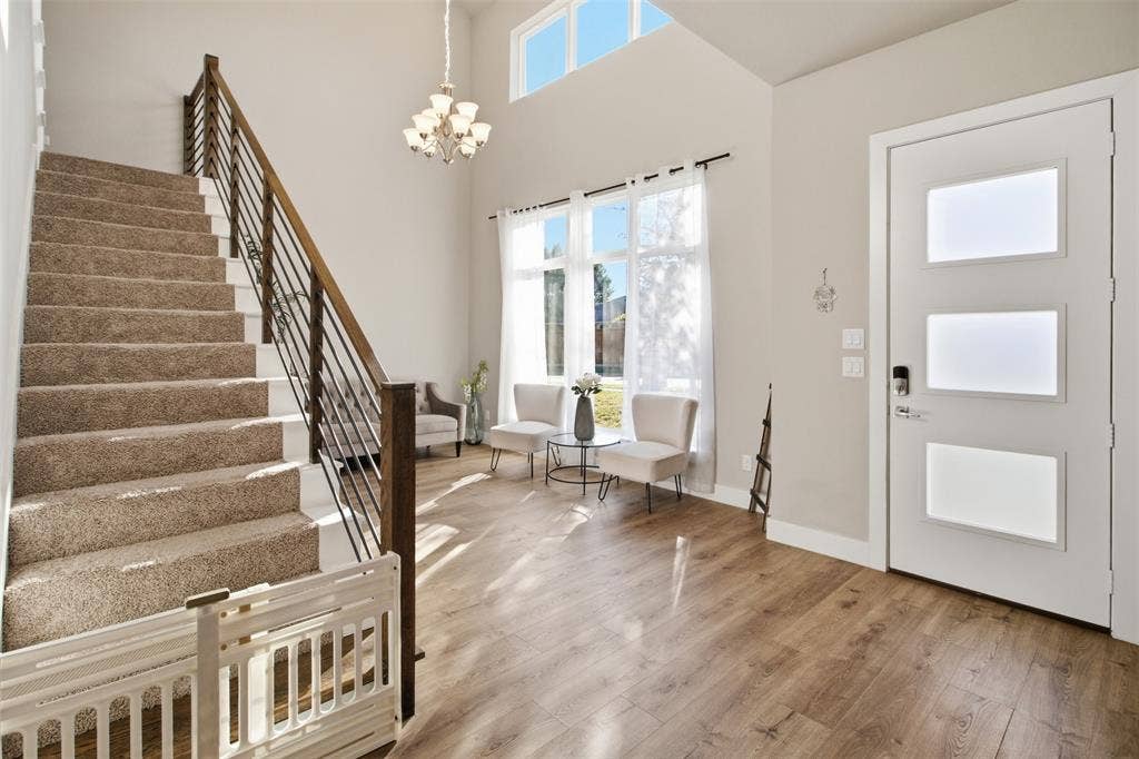 1408 Rockcliff Street, Plano, TX 75093 Foyer featuring high ceilings, wood-finish flooring, a staircase with horizontal metal railing, multi-pane transom and full-length windows, and a glass-paneled entry door
