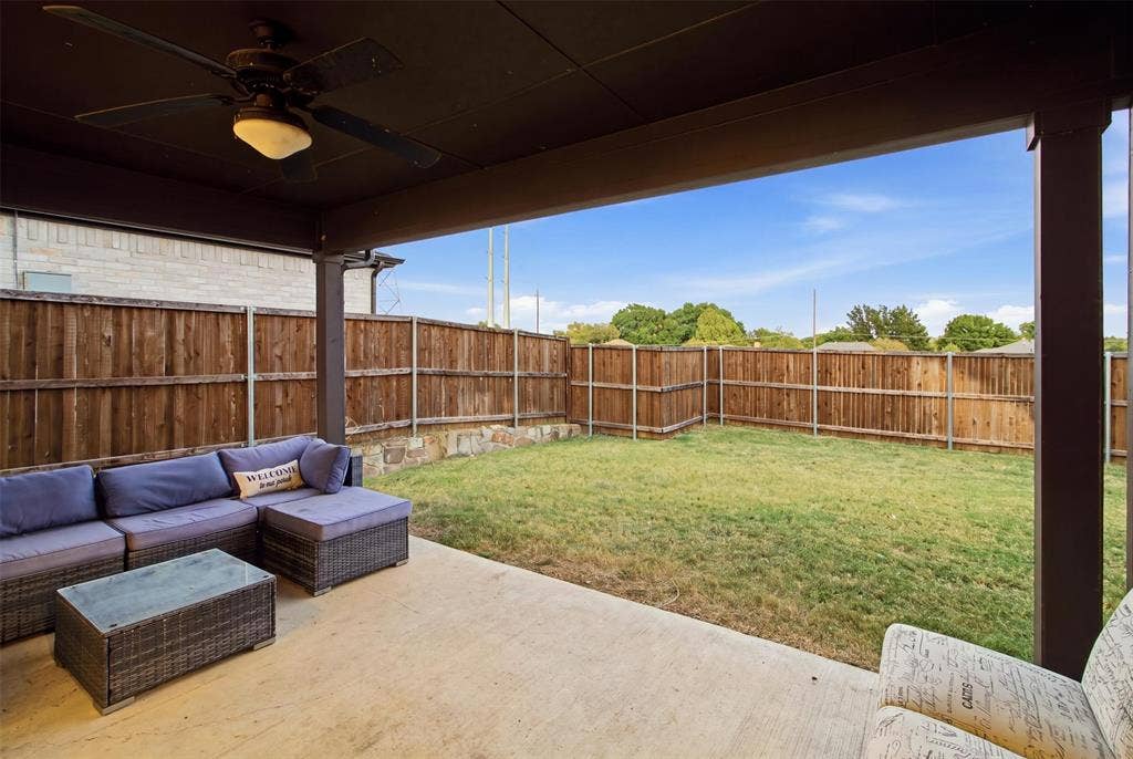 1408 Rockcliff Street, Plano, TX 75093 Covered patio featuring a ceiling fan, concrete flooring, stone retaining wall, and wood privacy fencing surrounding the backyard