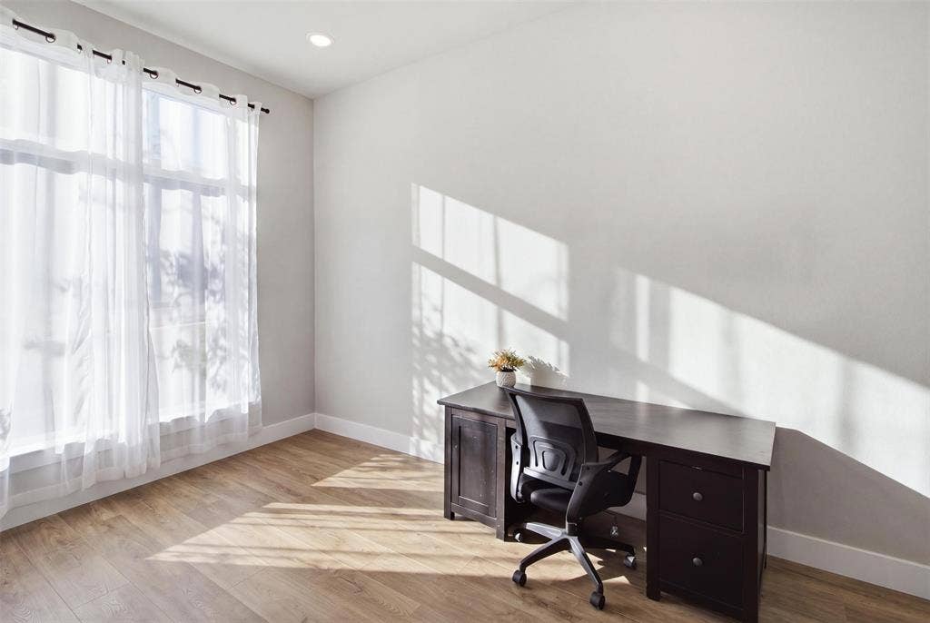 1408 Rockcliff Street, Plano, TX 75093 Room featuring wood-finish flooring, neutral wall paint, and a large window with tall glass panels, illuminated by recessed ceiling lighting