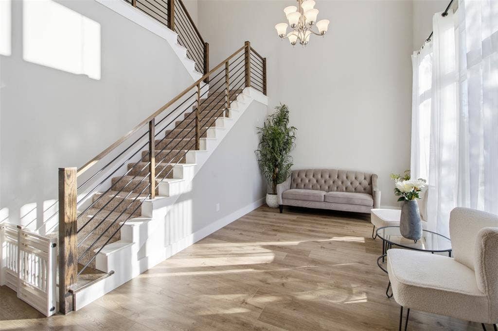 1408 Rockcliff Street, Plano, TX 75093 Double-height foyer featuring wood-finish flooring, a grand staircase with horizontal cable railing, and a multi-arm chandelier