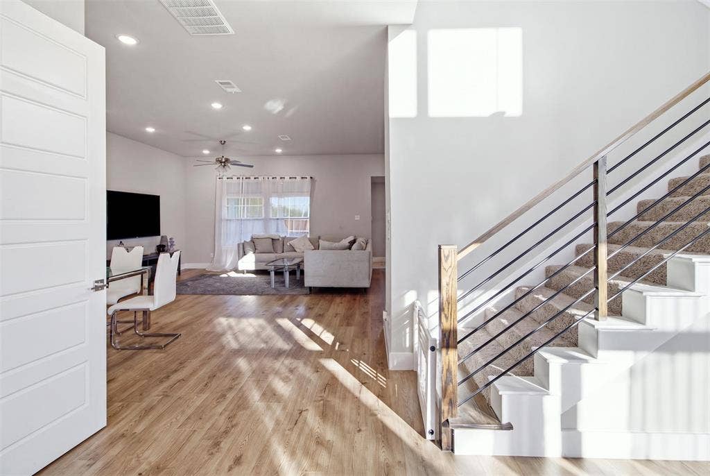 1408 Rockcliff Street, Plano, TX 75093 Open-concept interior featuring wood-finish flooring, recessed lighting, and a staircase with a wood handrail and horizontal metal balusters
