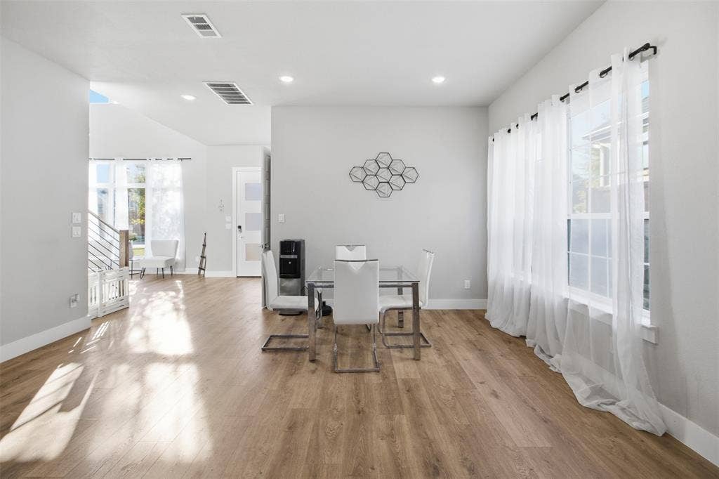 1408 Rockcliff Street, Plano, TX 75093 Open-concept interior featuring wood-finish flooring, recessed lighting, and large windows with horizontal muntins