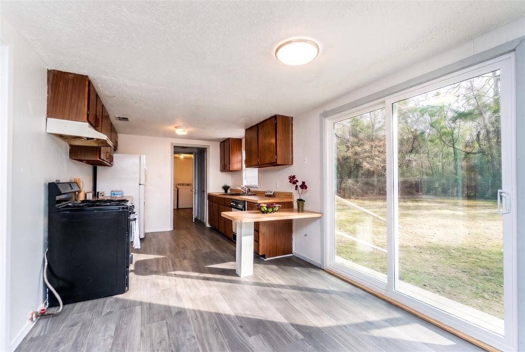 Kitchen featuring wood-finish cabinetry, built-in breakfast bar, wood-finish flooring, and sliding glass doors with exterior yard access