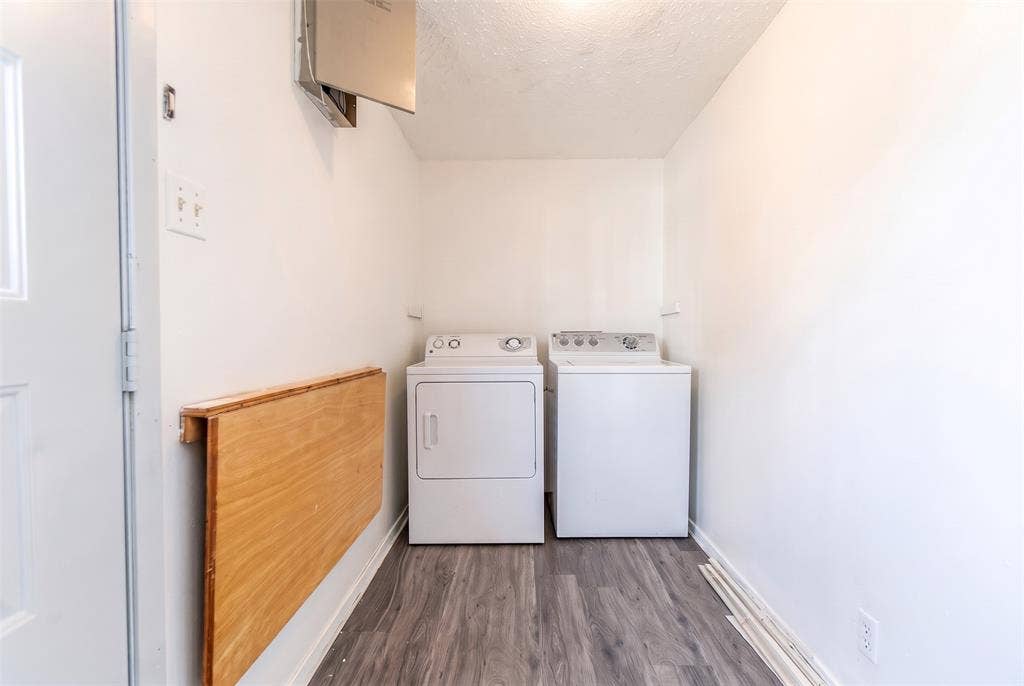 Dedicated utility space featuring wood-finish flooring and a wall-mounted fold-down wooden counter