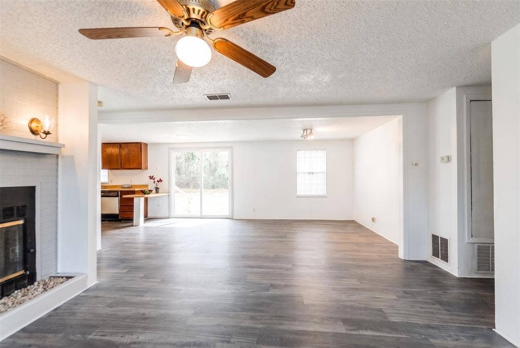 Painted brick fireplace, wood-finish flooring, ceiling fan, sliding glass door, and recessed lighting