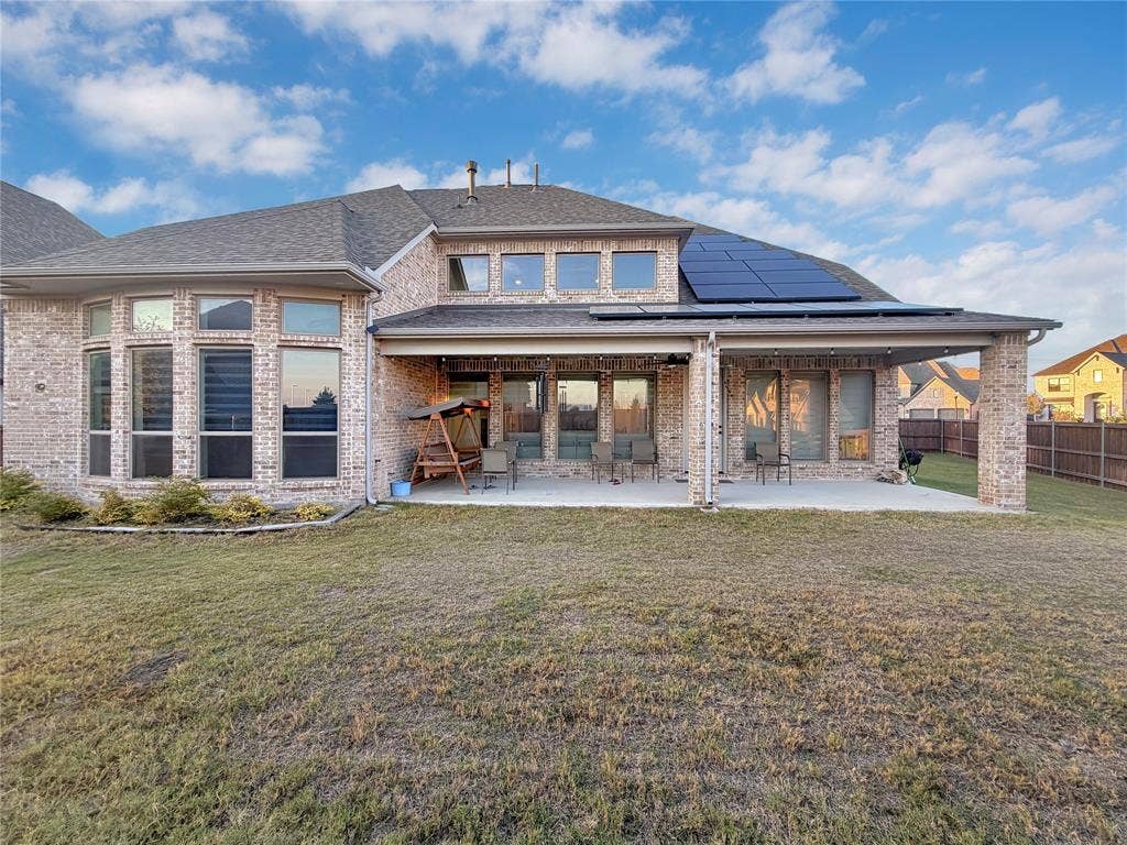 2251 Macy Way, Prosper, TX 75078 Brick exterior rear elevation featuring a covered patio, solar panels, and multi-pane window configurations