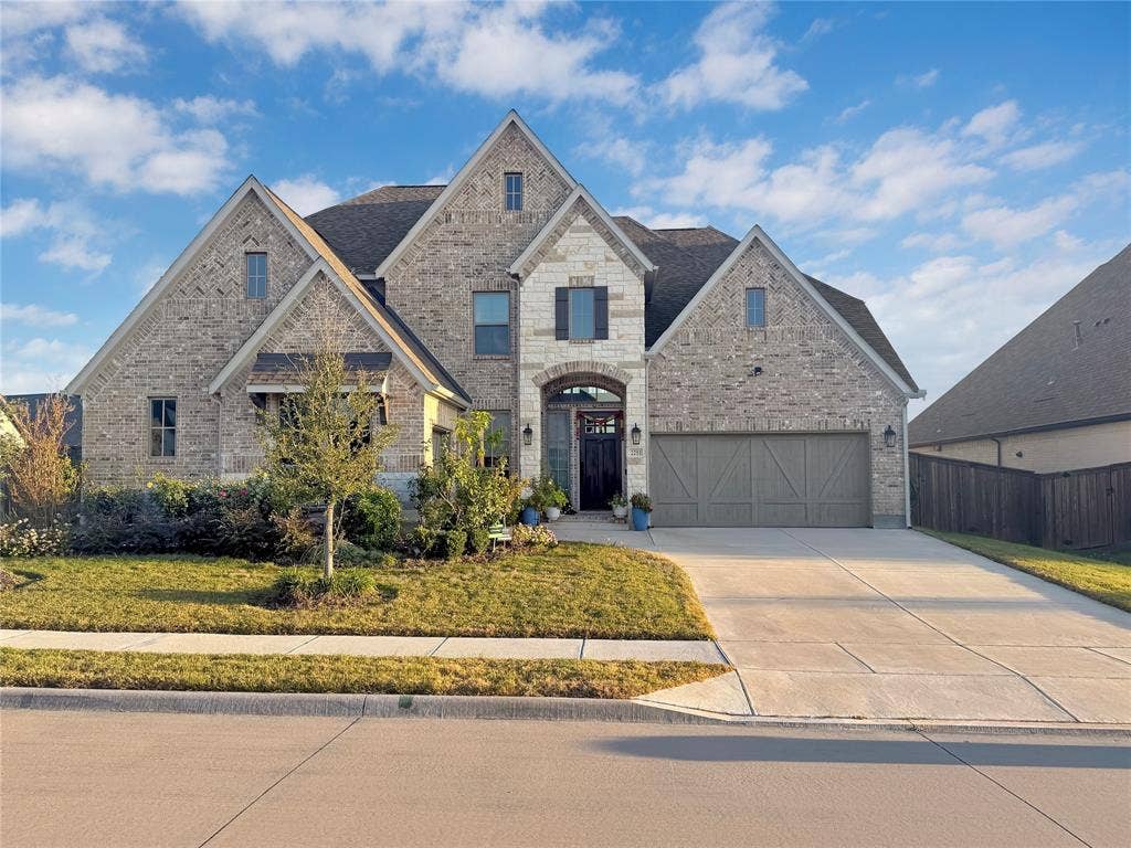 2251 Macy Way, Prosper, TX 75078 Multi-gabled brick and stone facade featuring an arched entryway, decorative wooden shutters, and an attached three-car garage
