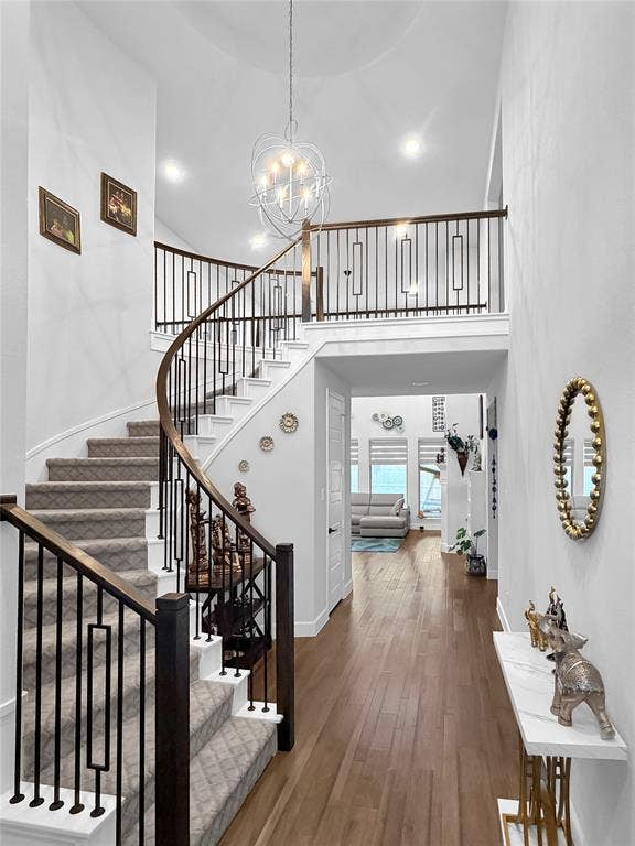 2251 Macy Way, Prosper, TX 75078 Grand foyer featuring a sweeping curved staircase with iron balusters and a wood handrail, polished wood-finish flooring, and a multi-light contemporary orb pendant fixture