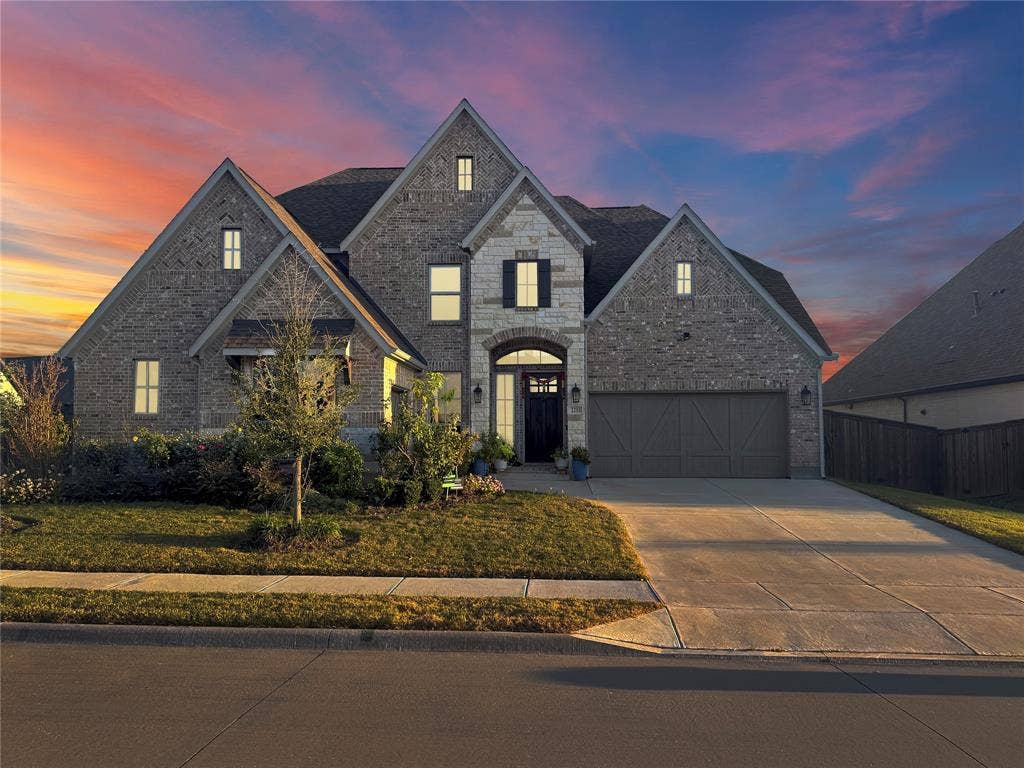 2251 Macy Way, Prosper, TX 75078 Multi-gabled exterior featuring brick and stone masonry, decorative shutters, arched entryway, and attached garage