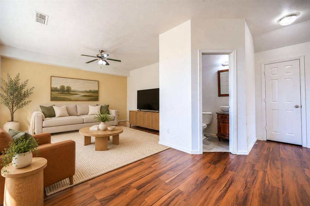 2709 Maci Court, Seagoville, TX 75159 Wood-finish flooring, ceiling fan with integrated lighting, and a doorway leading to a bathroom featuring a wood-finish vanity and vessel sink