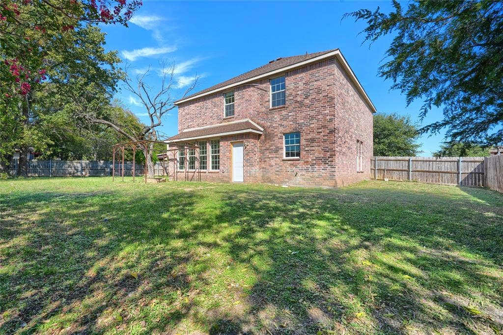 2709 Maci Court, Seagoville, TX 75159 Two-story brick exterior featuring a shingled roof, multiple windows with grid detailing, and a fenced-in rear yard
