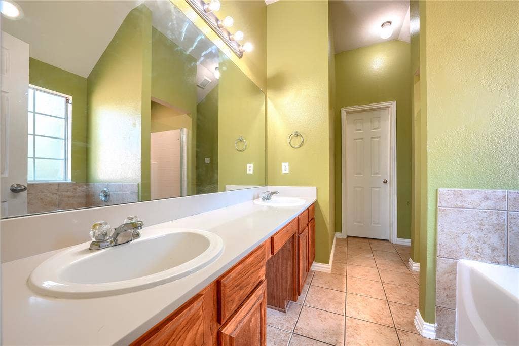 2709 Maci Court, Seagoville, TX 75159 Double vanity featuring light-toned solid surface countertops, wood cabinetry, tile flooring, and a full-width wall mirror