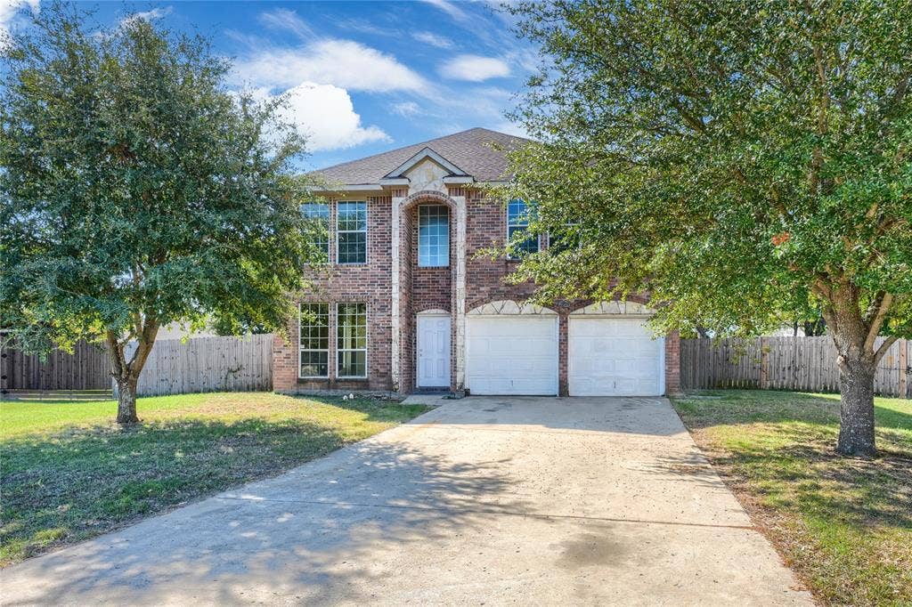 2709 Maci Court, Seagoville, TX 75159 Two-story brick exterior featuring a multi-gabled roofline, an arched entryway, and an attached two-car garage