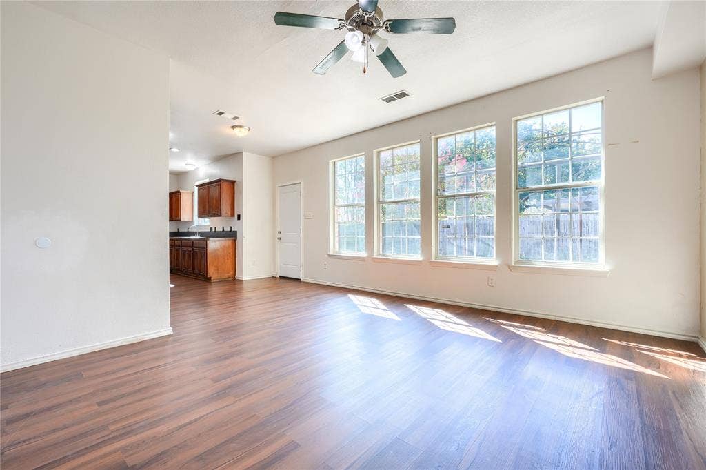 2709 Maci Court, Seagoville, TX 75159 Open-concept room featuring wood-finish flooring, a ceiling fan with integrated lighting, and a row of large windows