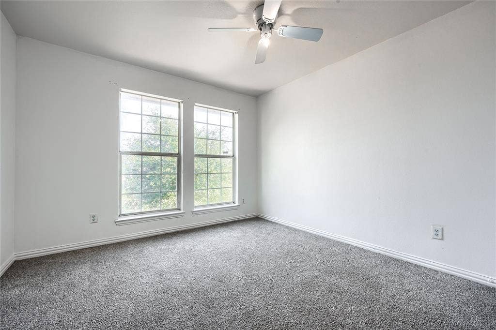 2709 Maci Court, Seagoville, TX 75159 Interior room featuring neutral wall paint, wall-to-wall carpeting, dual grid-patterned windows, and a ceiling fan with integrated lighting