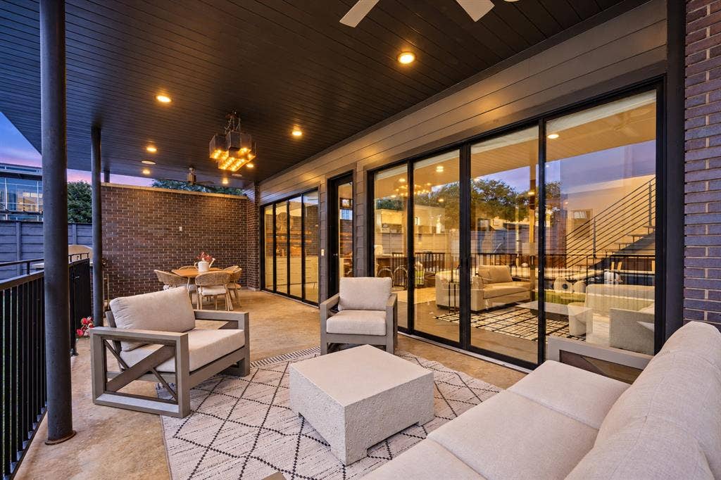An outdoor living room made for lingering. Covered lounge and dining areas, ceiling fans, and expansive glass doors connect the home’s interiors to evenings outside.