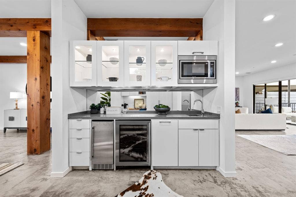 An entertaining station with beverage storage, a prep sink, and glass-front cabinetry keeps hosting effortless.