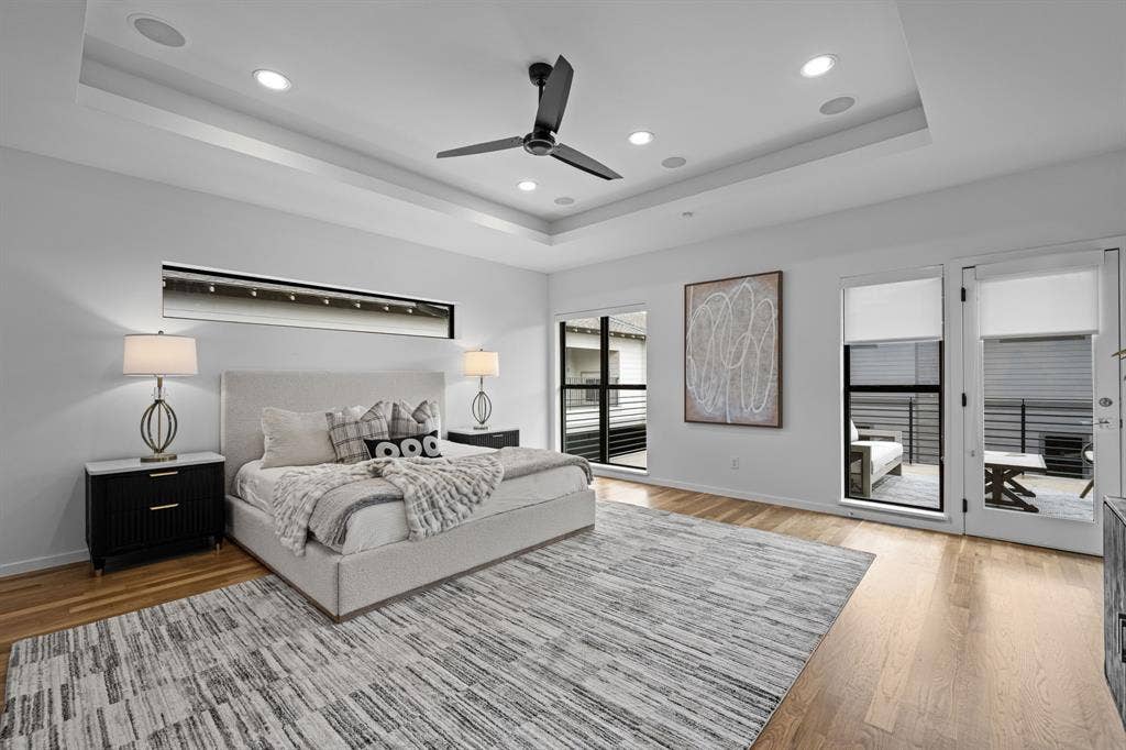 Hardwood floors, a tray ceiling, and direct balcony access define the primary retreat.