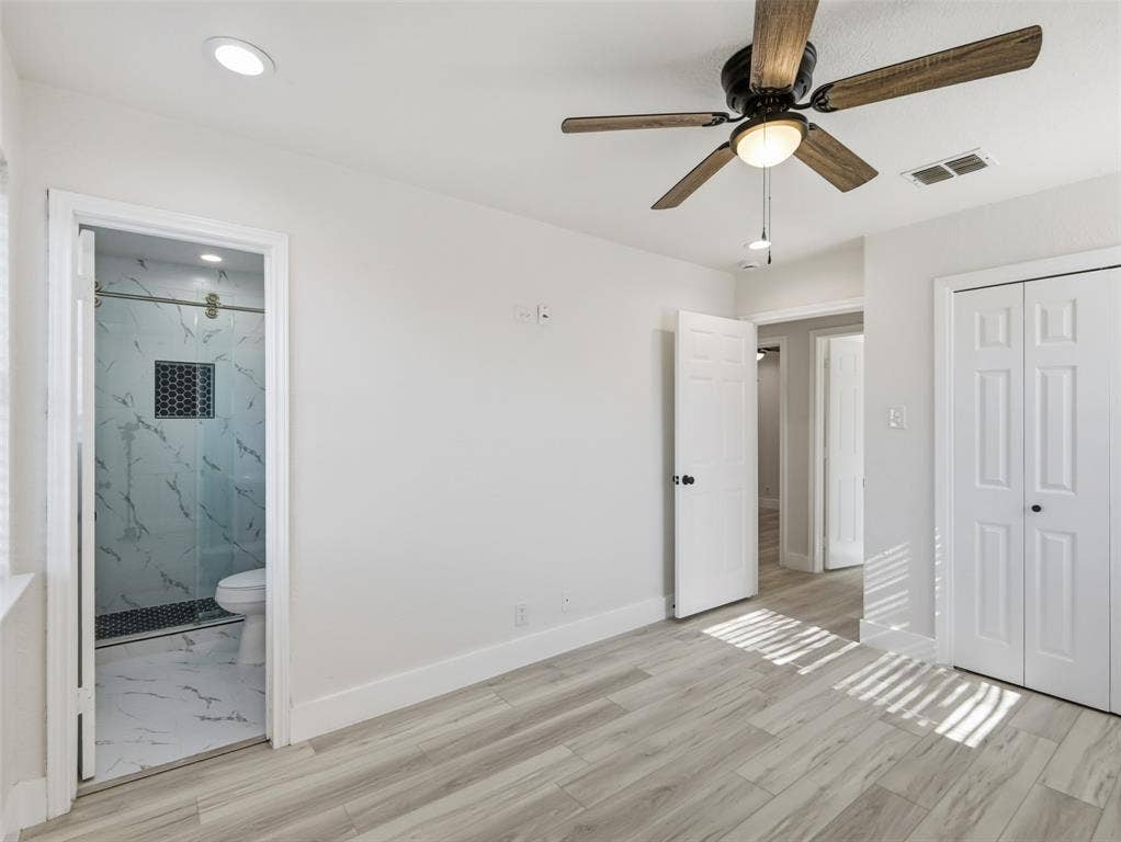 Room featuring wood-finish flooring, a ceiling fan with integrated lighting, recessed lighting, and a bathroom with a glass-enclosed shower and patterned tile inlay