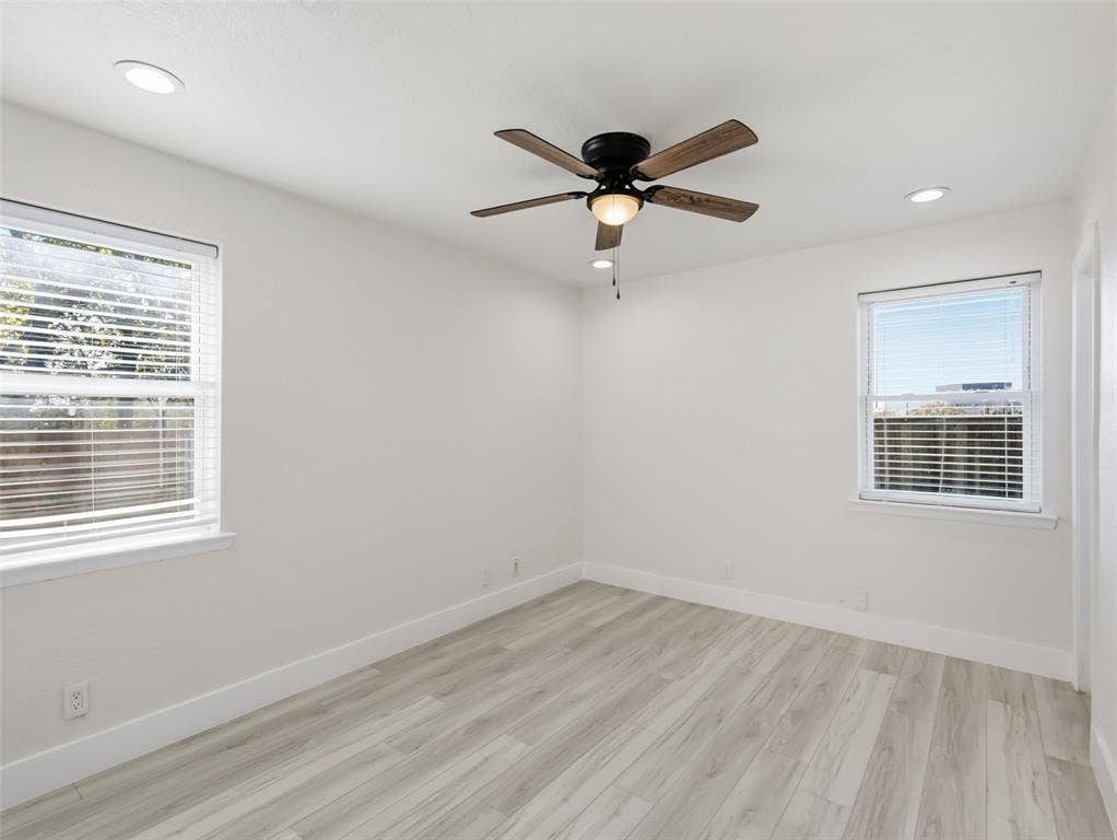 Interior space featuring wood-finish flooring, recessed lighting, a multi-blade ceiling fan with an integrated light fixture, and two windows with horizontal blinds