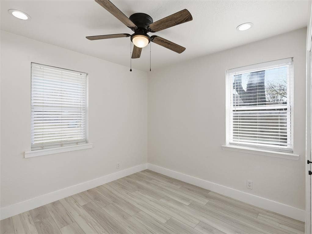 Room featuring wood-finish flooring, recessed lighting, a ceiling fan with integrated light, and two windows with blinds