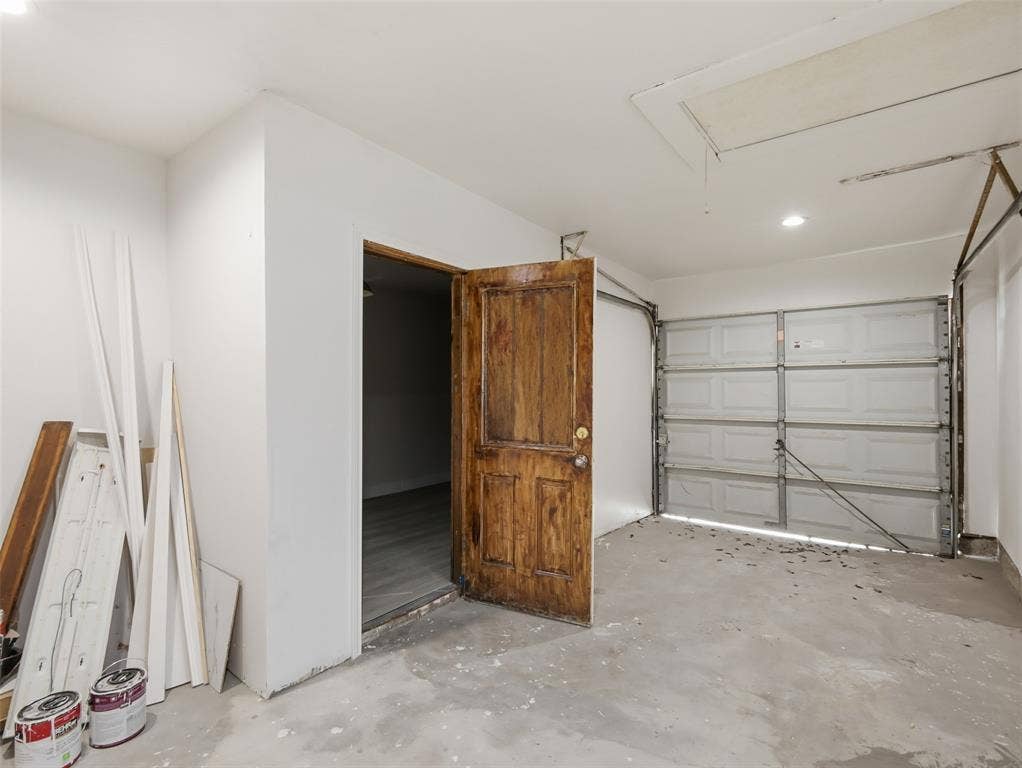 Enclosed garage featuring a concrete floor, a paneled metal overhead door, and a solid wood entry door