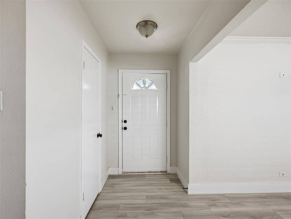 Entryway featuring wood-finish flooring, a six-panel door with a half-moon light, and a flush-mount ceiling fixture