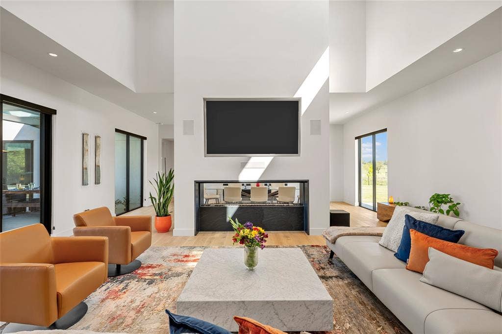 356 Bold Springs Court, West, TX 76691 Double-height ceilings featuring recessed lighting, Large glass sliding doors, and a central dual-sided linear fireplace with surround sound throughout.