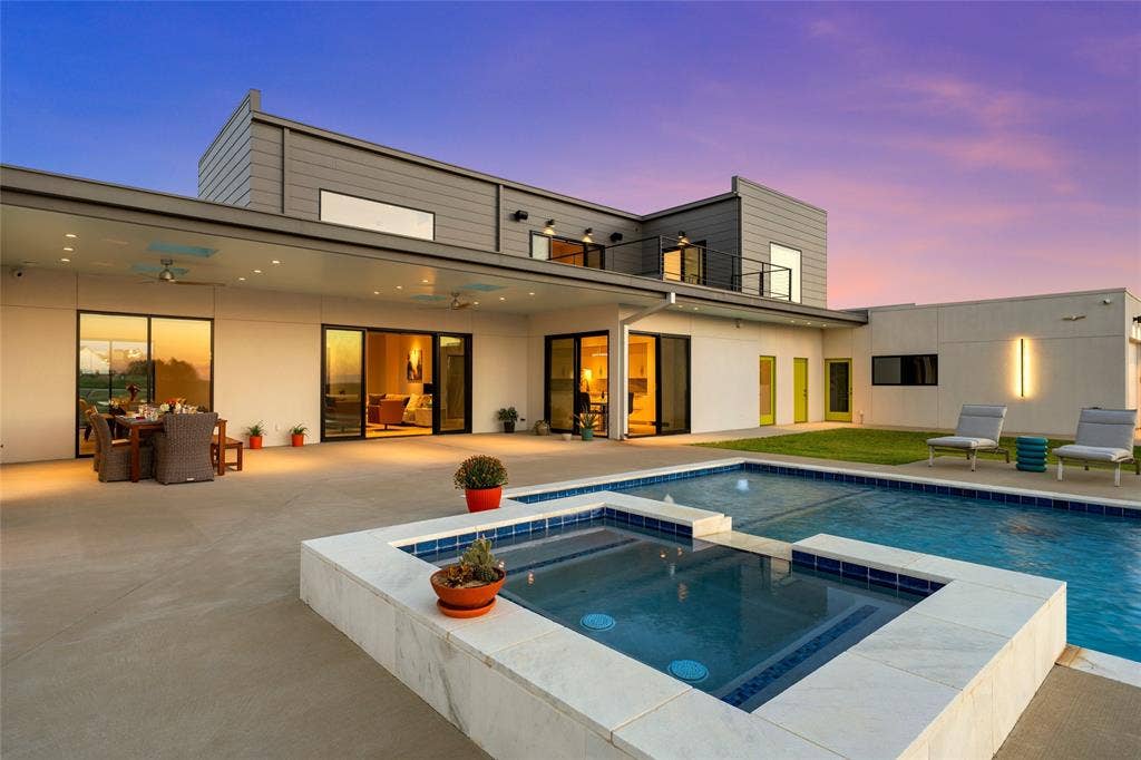 356 Bold Springs Court, West, TX 76691 Contemporary exterior featuring a covered patio, integrated pool and spa with stone-style coping, and expansive sliding glass doors