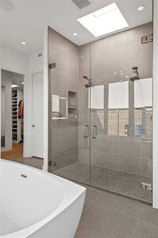 356 Bold Springs Court, West, TX 76691 Walk-in shower featuring a frameless glass enclosure, ceiling skylight, dual-head shower system, recessed shelving, and a textured stone-finish floor