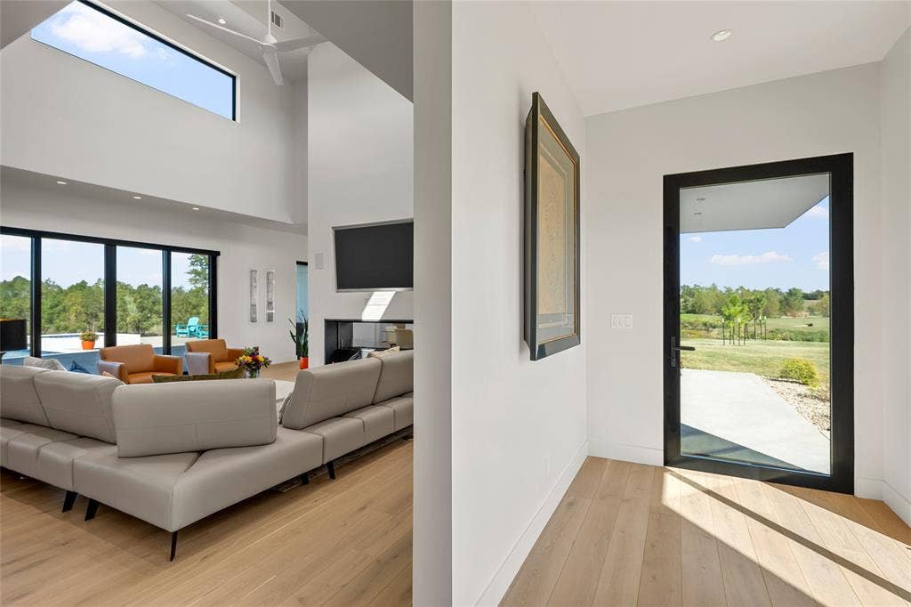 356 Bold Springs Court, West, TX 76691 Open-concept interior featuring double-height ceilings, wood flooring, recessed lighting, and a modern kitchen with integrated cabinetry.