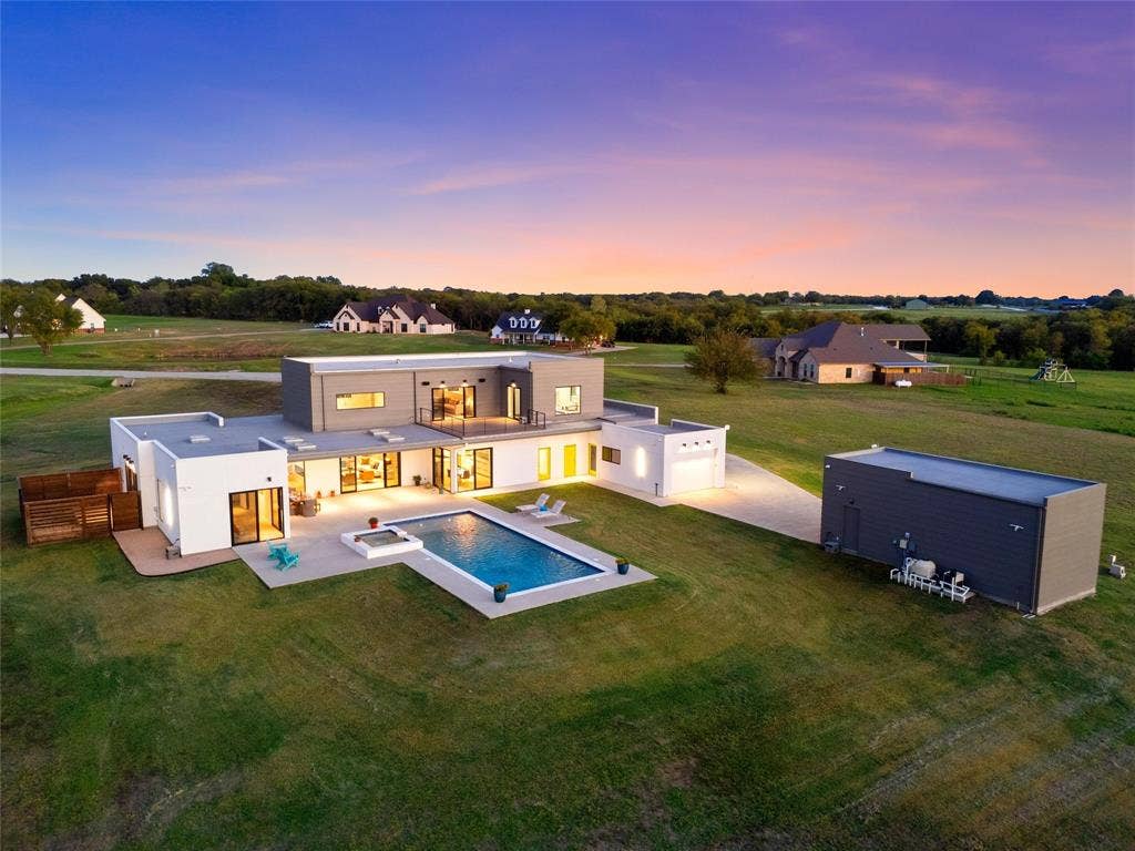 356 Bold Springs Court, West, TX 76691 Contemporary multi-level exterior featuring stucco and siding, a rectangular swimming pool with an integrated spa, a second-story balcony, and a detached RV/Tractor garage with parallel shop.