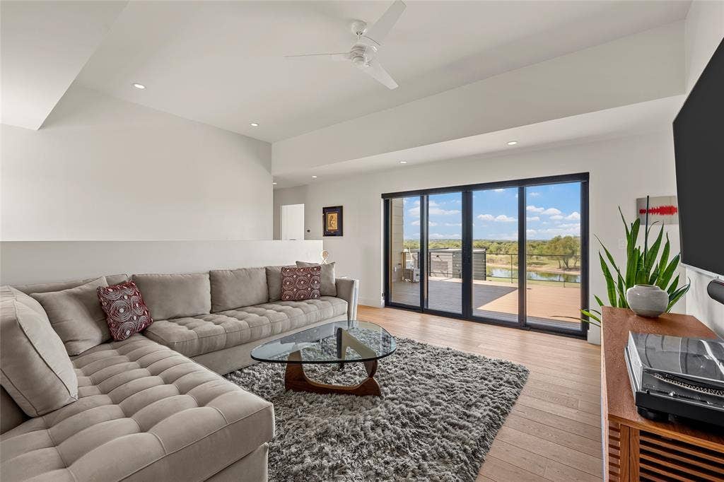 356 Bold Springs Court, West, TX 76691 Living area featuring high tray ceilings, wood-flooring, recessed lighting, a modern ceiling fan, and large-format sliding glass doors. Open to living room with clear safety glass and private pocket doors.