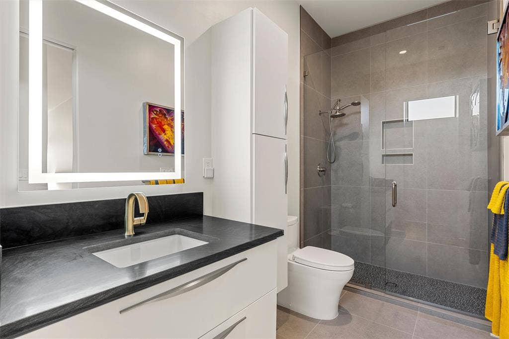 356 Bold Springs Court, West, TX 76691 Modern bathroom featuring an integrated LED-lighted mirror, Quartzite vanity countertop with an undermount sink, ample storage, and a walk-in shower with custom tile work surround and a recessed shampoo niche