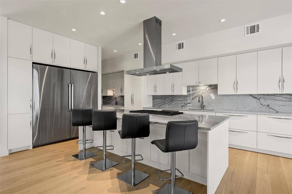 356 Bold Springs Court, West, TX 76691 Kitchen featuring white cabinetry, Quartzite countertops with matching backsplash, Dacor 36 inch refrigerator and 36 inch freezer, center island with built-in Dacor cooktop, and wood flooring