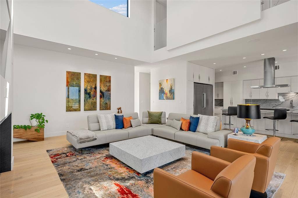 356 Bold Springs Court, West, TX 76691 Open-concept interior featuring double-height ceilings, light wood flooring, recessed lighting, and a modern kitchen with integrated cabinetry and stainless-steel range hood