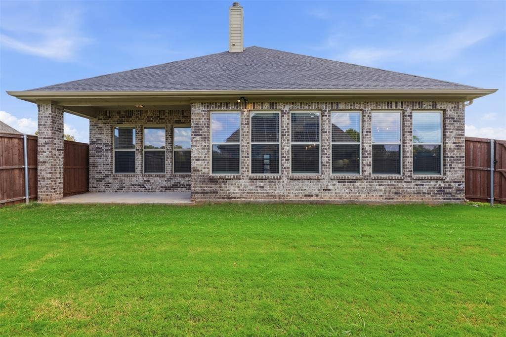 Brick exterior featuring a covered patio, hipped roofline, and multiple grid-pattern windows