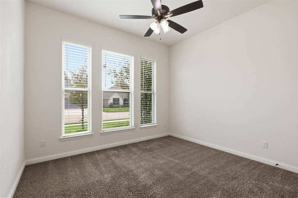Room featuring neutral walls, carpeting, triple window configuration with horizontal blinds, and a ceiling fan with light kit