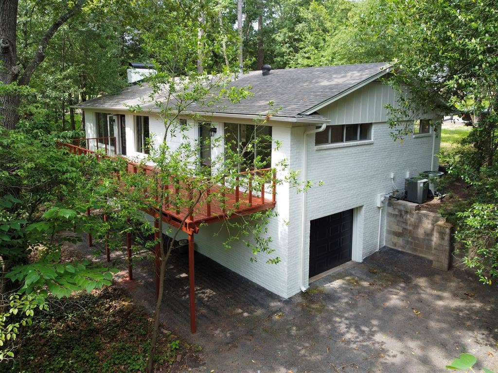431 Lone Star Lane, Hideaway, TX 75771 Painted brick exterior featuring an elevated wood deck, horizontal windows, and an attached lower-level garage