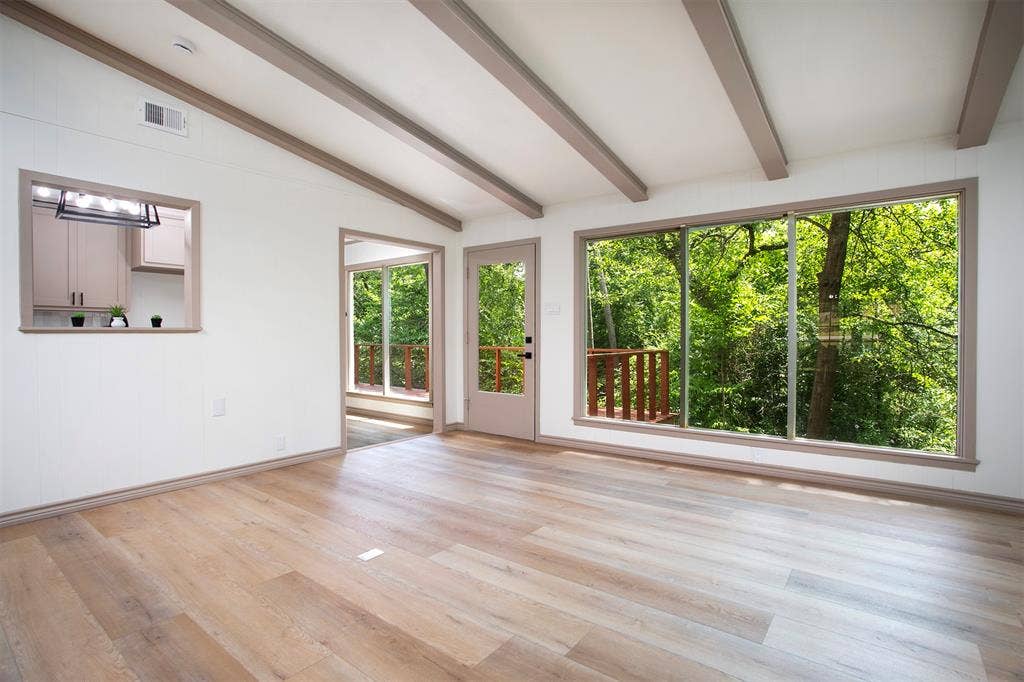 431 Lone Star Lane, Hideaway, TX 75771 Living area featuring wood-finish flooring, exposed ceiling beams, expansive floor-to-ceiling windows, and a pass-through opening to the kitchen area