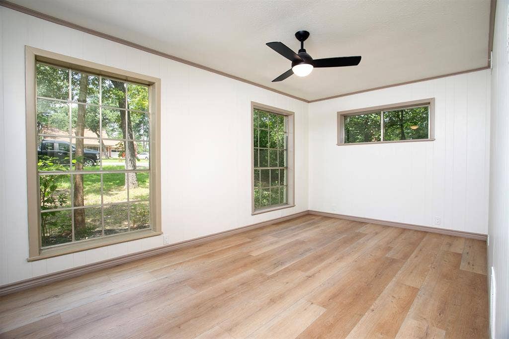 431 Lone Star Lane, Hideaway, TX 75771 Interior space featuring wood-finish flooring, white wall paneling, multiple grid-style windows, and a matte black ceiling fan with integrated light