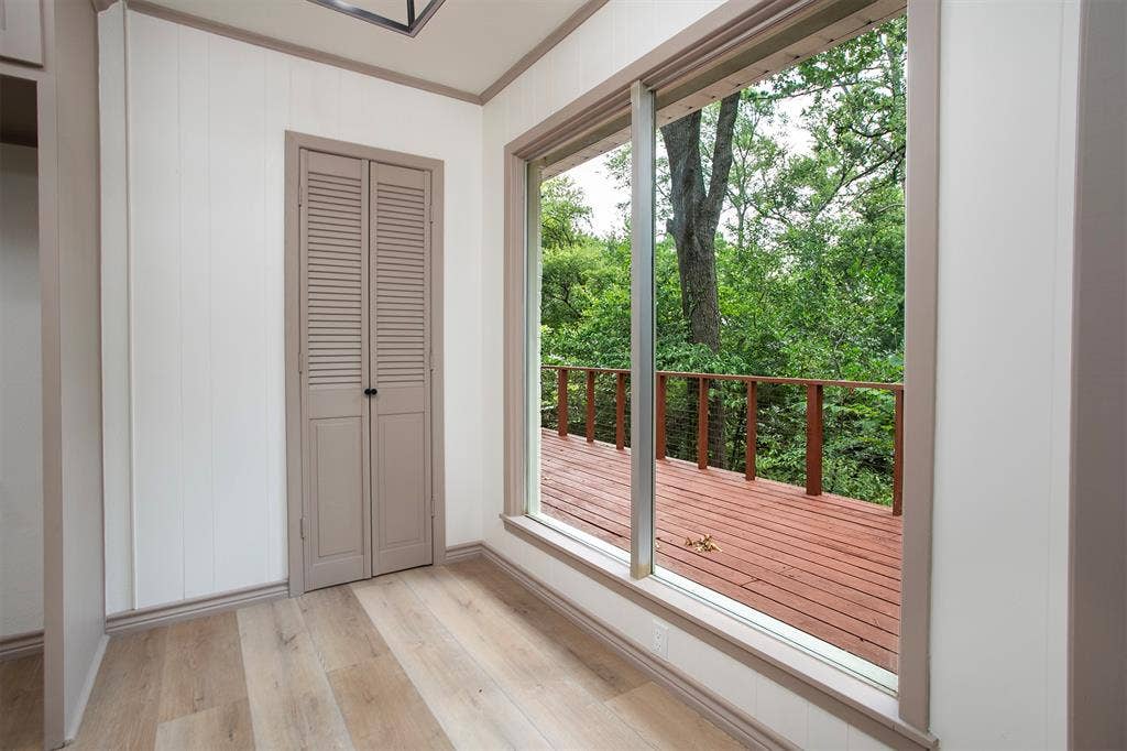 431 Lone Star Lane, Hideaway, TX 75771 Wood-finish flooring, vertical paneling, louvered closet doors, and a large floor-to-ceiling window showcasing an exterior wood deck