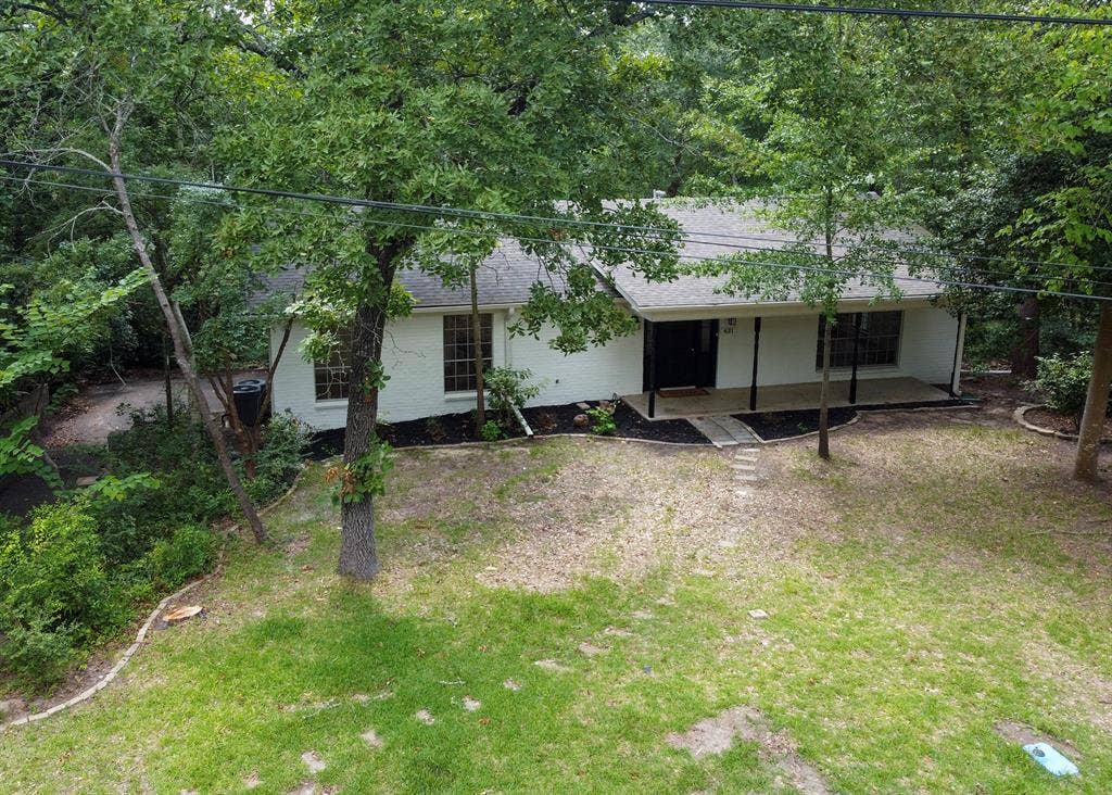 431 Lone Star Lane, Hideaway, TX 75771 Painted brick exterior featuring a covered front porch, multi-pane windows, and a mature tree-lined lot