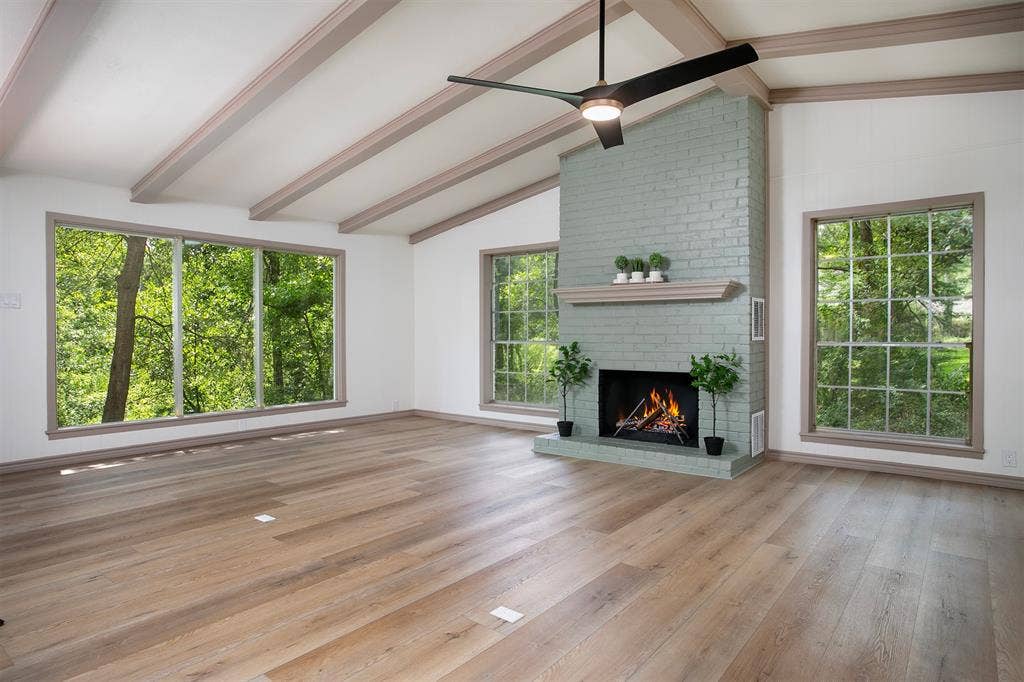 431 Lone Star Lane, Hideaway, TX 75771 Vaulted ceilings with exposed beams, wood-finish flooring, painted brick fireplace with a mantel, and oversized windows